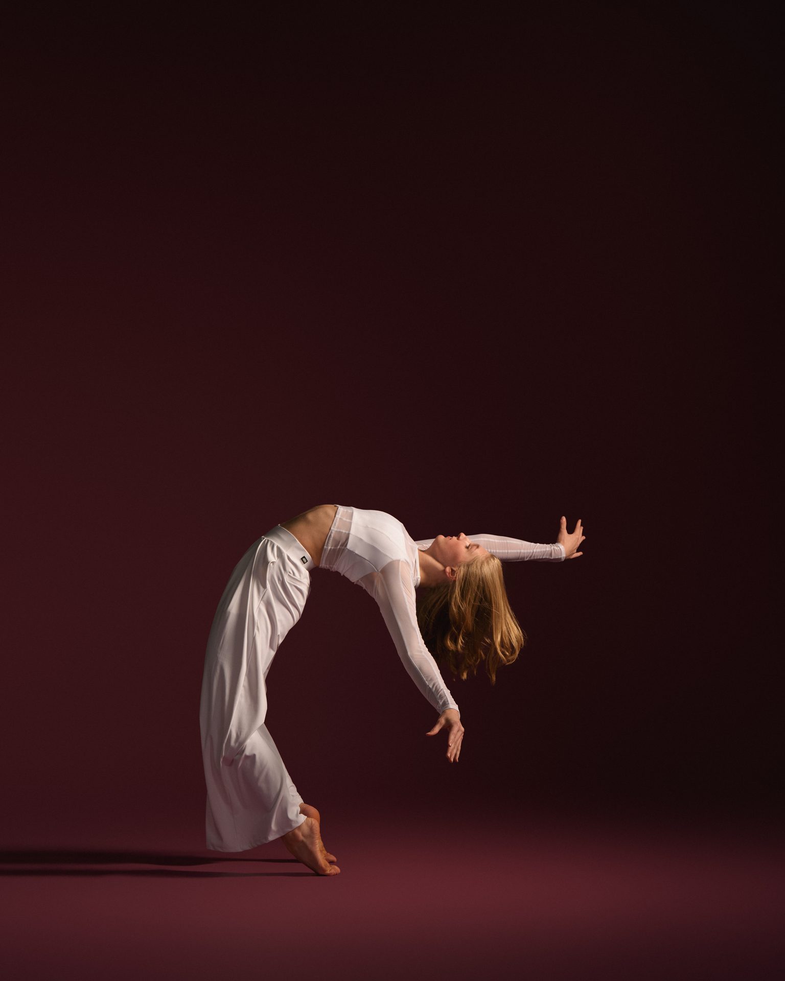 Performer in a flowing backbend on stage lighting